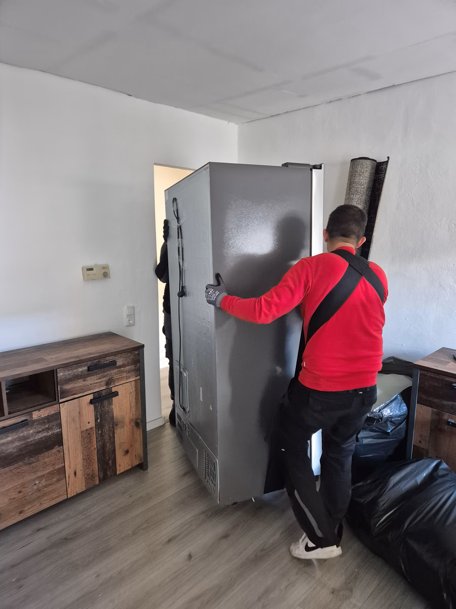 Mitarbeiter von G&N Transporte trägt ein Gerät aus einer geräumten Wohnung in Straubing